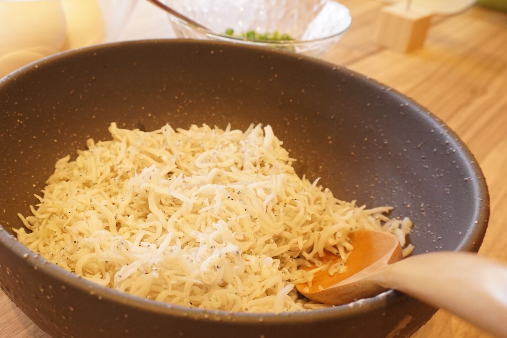 A frying pan with shredded cheese being stirred.