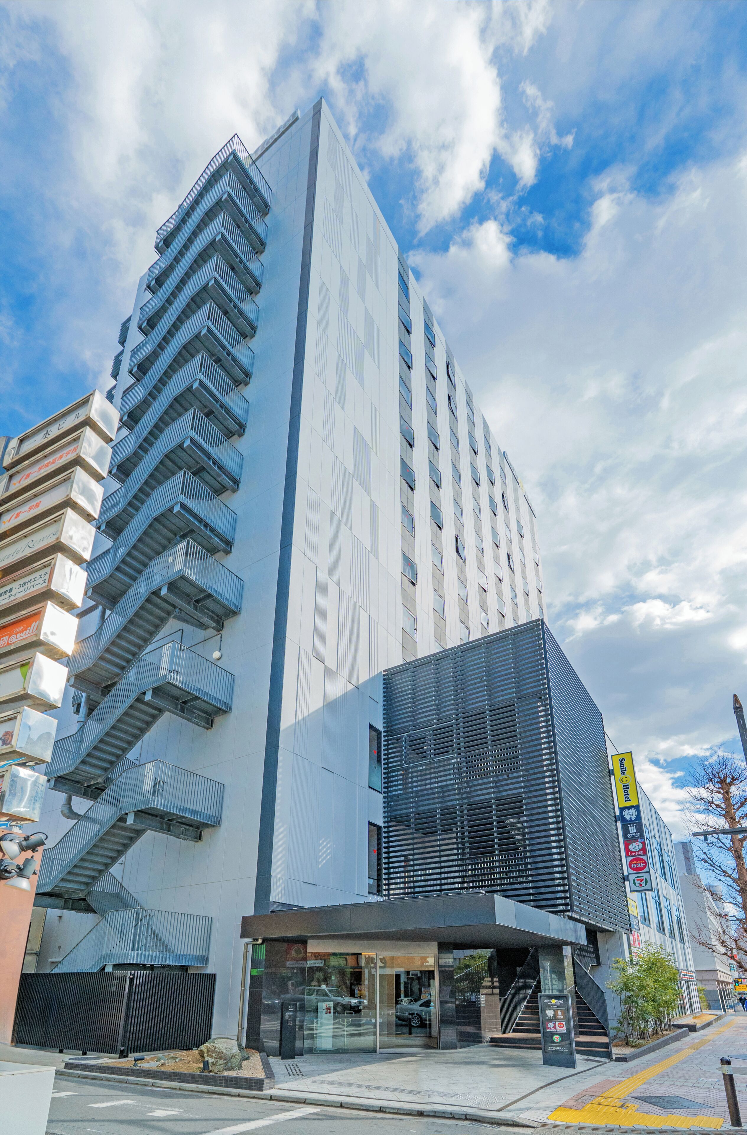 Un edificio moderno con una escalera destacada, entrada de cristal y un letrero que indica un hotel.