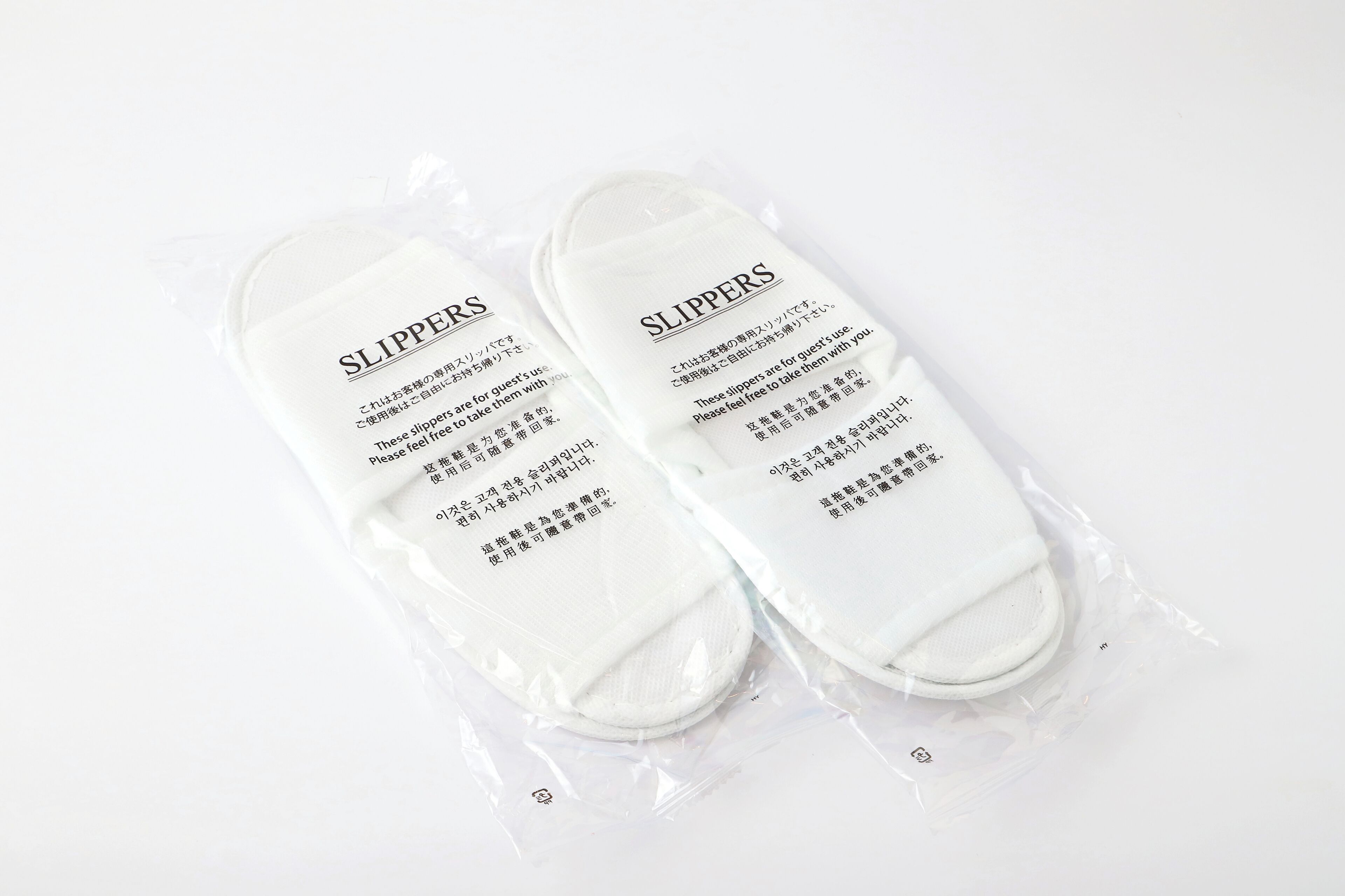 Une paire de chaussons emballés dans un sac en plastique, avec du texte imprimé dessus.