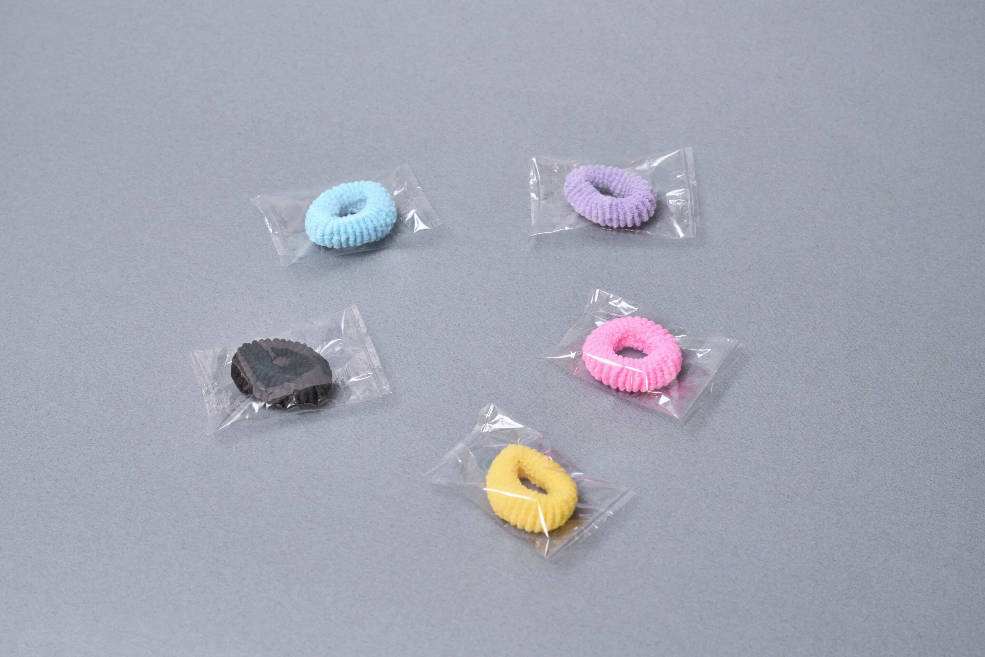 Five small, individually wrapped objects on a grey surface.