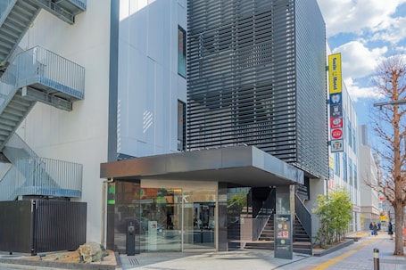 A modern building with a glass entrance, a staircase, and a sign for Smile Hotel.