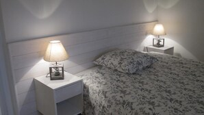 Un dormitorio con cama, dos mesitas de noche y lámparas.