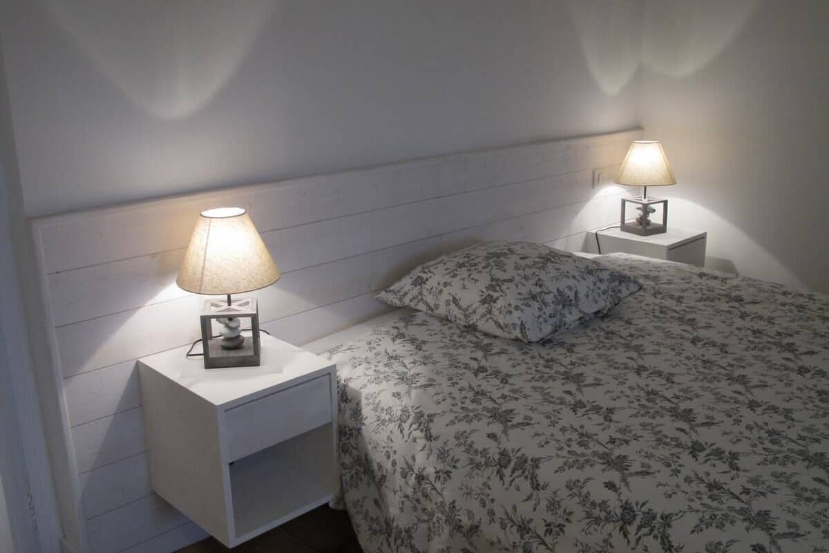Un dormitorio con cama, dos mesitas de noche y lámparas.