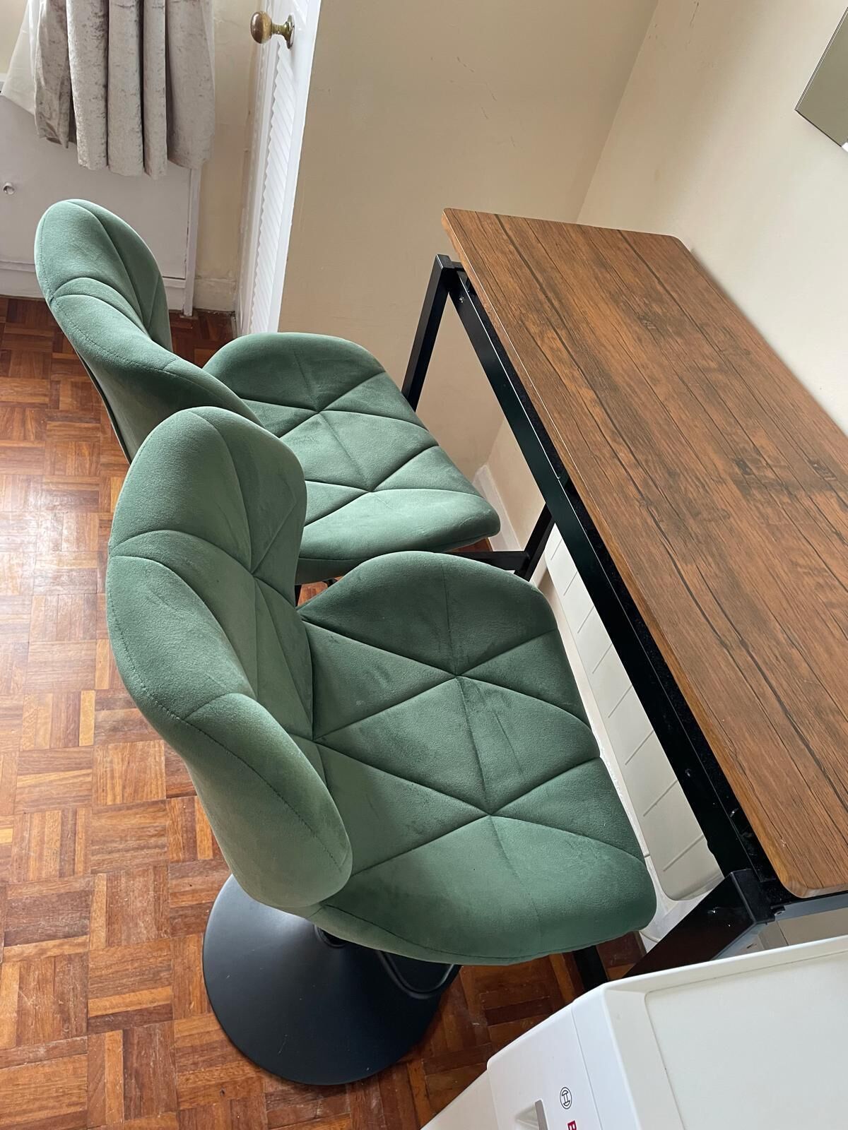 A dining area with a wooden table and two green upholstered chairs.