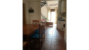 A kitchen with a dining area, a washing machine, and a staircase leading to another room.