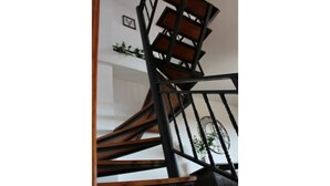 A spiral staircase with wooden steps and black railings.