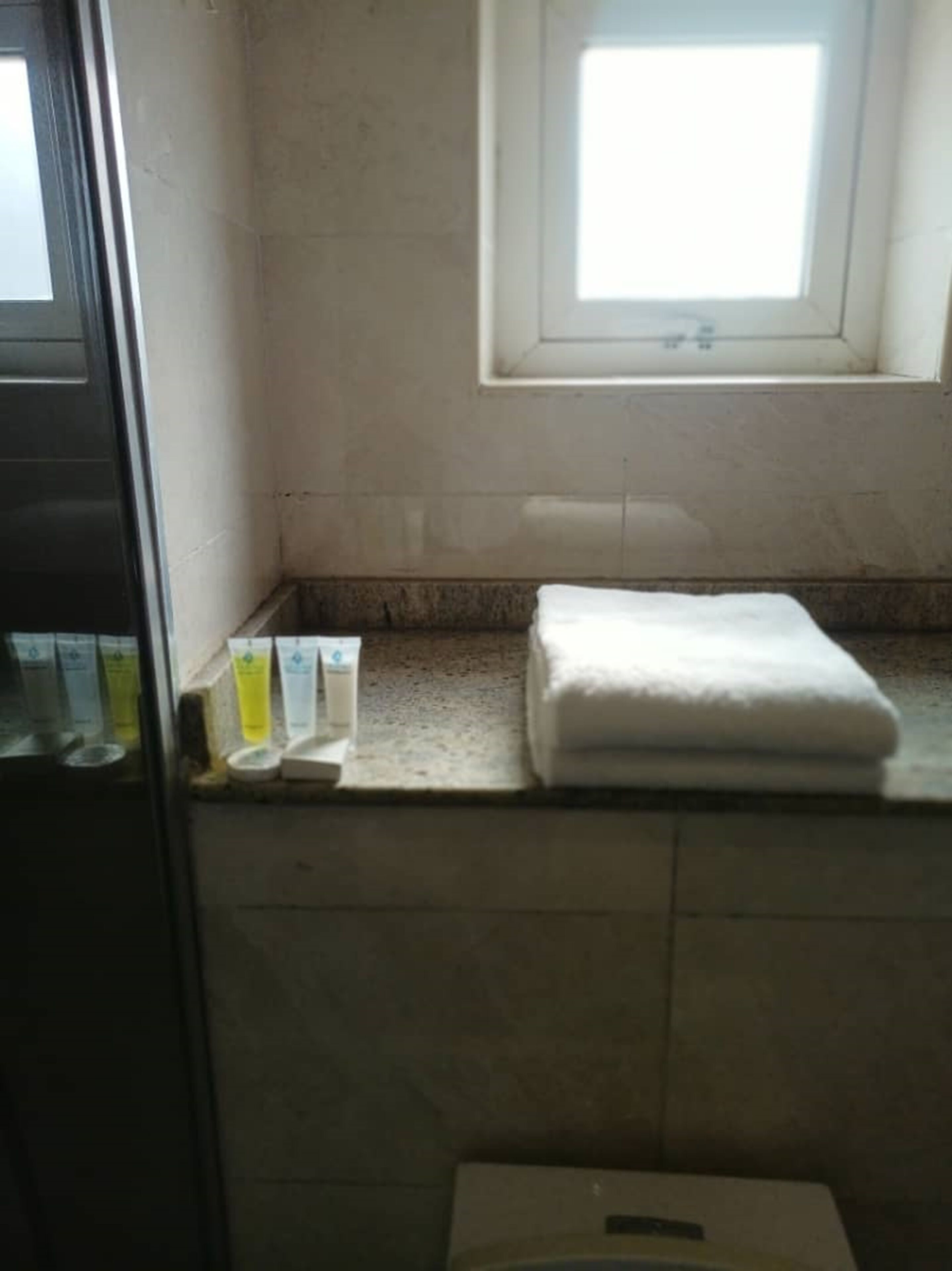 A bathroom with a window, a towel, and toiletries on the counter.