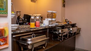 A buffet setup with various food containers and a juice dispenser. - Ace Premier Hotel (Abuja)