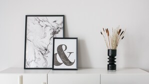 A white console table with two framed artworks, a candle, and a vase with reeds. - Spacious 1BD Apartment near HELEXPO Marousi (Marousi)