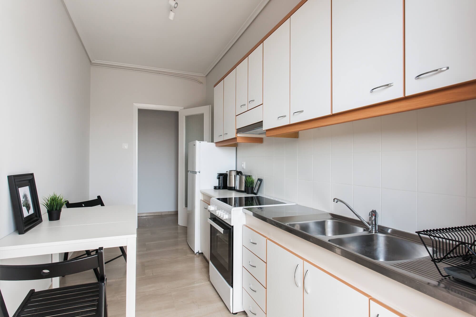 A modern kitchen with white cabinets, a stainless steel sink, and a built-in oven.
