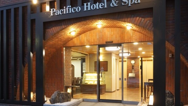 The Pacifico Hotel & Spa entrance with a brick facade, glass doors, and a sign above the entrance. - Pacifico Hotel Spa (Iwaki)