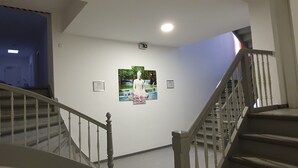 A staircase with a handrail, a wall with framed pictures, and a ceiling light. - Trang Hotel (Rastatt)