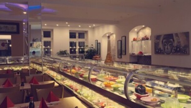 A modern hotel lobby with a food display, seating area, and decorative elements. - Trang Hotel (Rastatt)