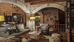 A cozy living room with a stone fireplace, wooden beams, and comfortable seating. - Simurg Inn (Ayvacik)