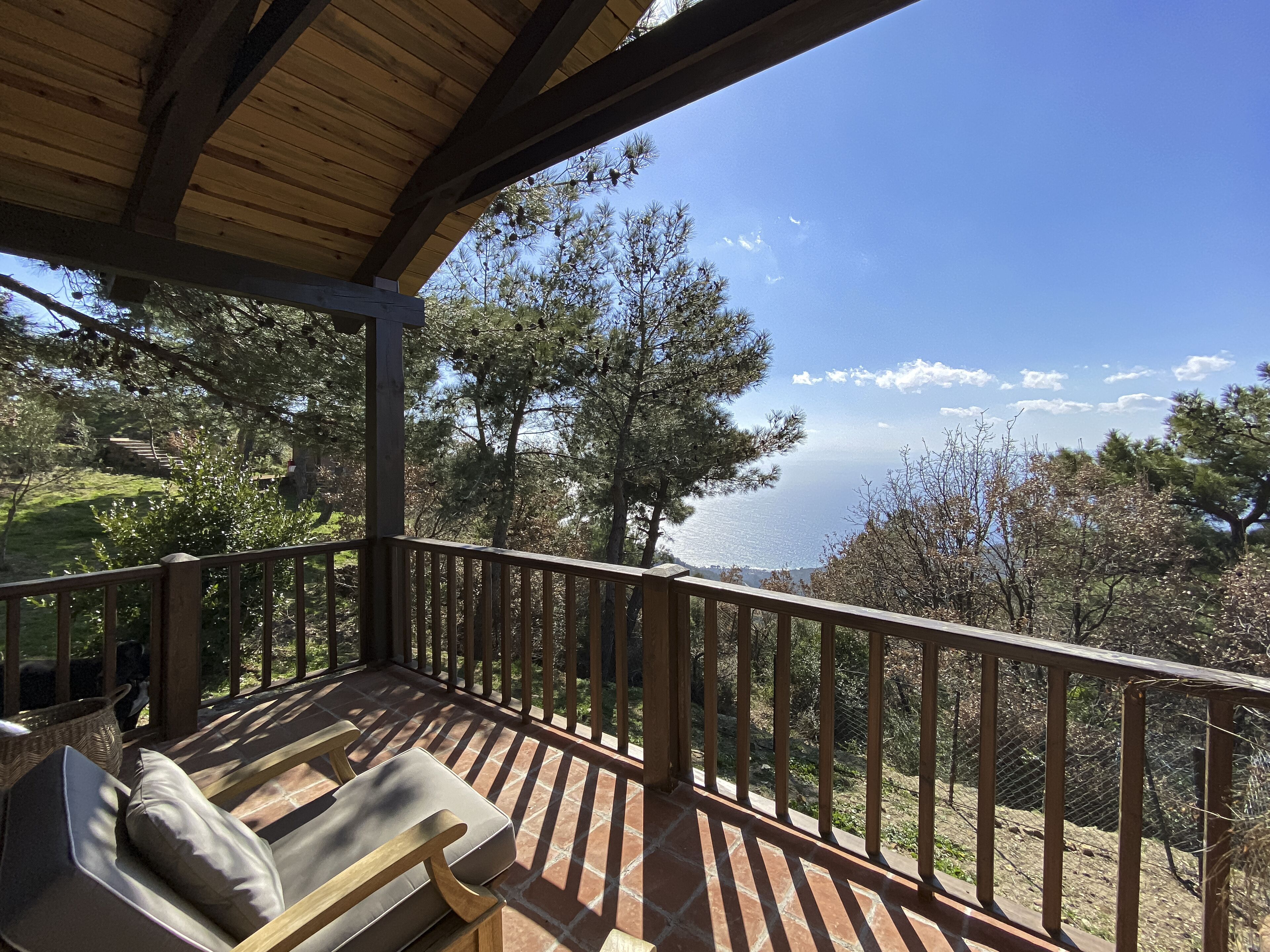 A wooden deck with a view of the ocean and trees.