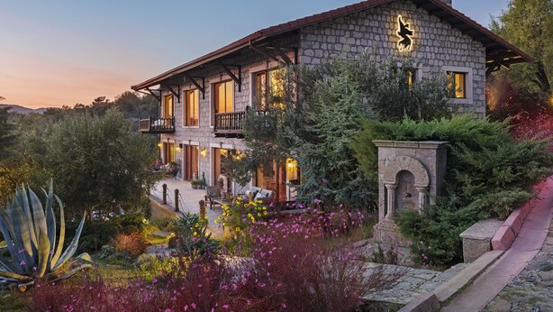 A stone building with a balcony, surrounded by lush gardens and a stone pathway. - Simurg Inn (Ayvacik)