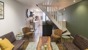 A modern living room with a wooden coffee table, leather sofas, and a staircase leading to a kitchen.