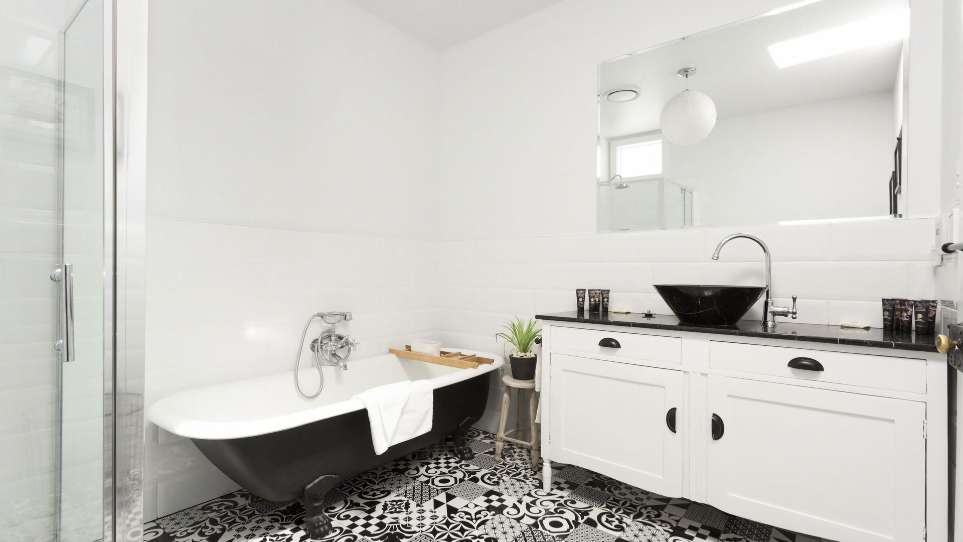 A modern bathroom with a freestanding bathtub, a black sink, and a white vanity.