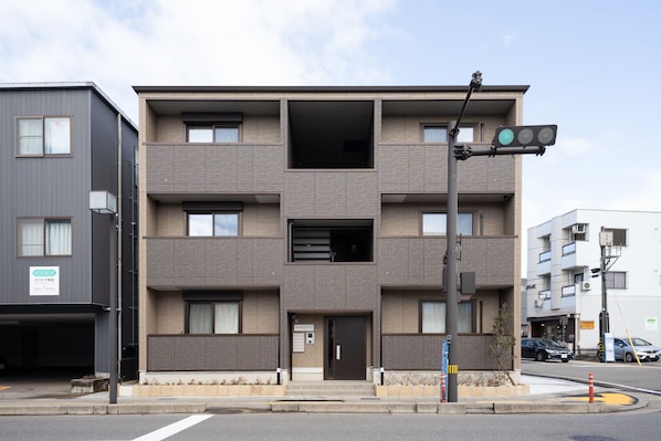 A multi-story building with a modern design, featuring a central entrance with a door and windows on each floor.