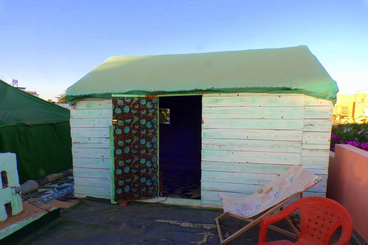 A small, single-room structure with a green door and a white exterior.