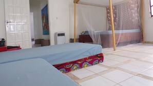 A bedroom with a bed, a mosquito net, a heater, and a door. - Le Triskell Auberge - Hostel (Nouakchott)