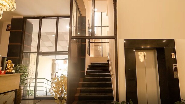 Un interior moderno con una escalera que lleva a un segundo piso, un ascensor y vistas al exterior a través de amplios ventanales.