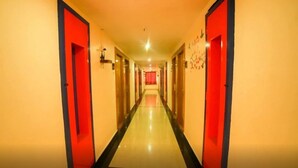 Un pasillo de hotel con puertas rojas y un diseño largo y estrecho.
