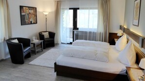 A hotel room with a large bed, a chair, a desk, and a window with curtains. - Landhotel Rebstock (Oberkirch)