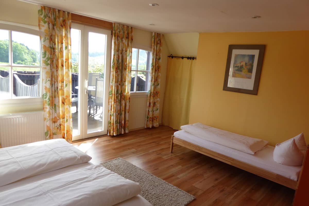 A room with two beds, a window with curtains, a radiator, and a painting on the wall.