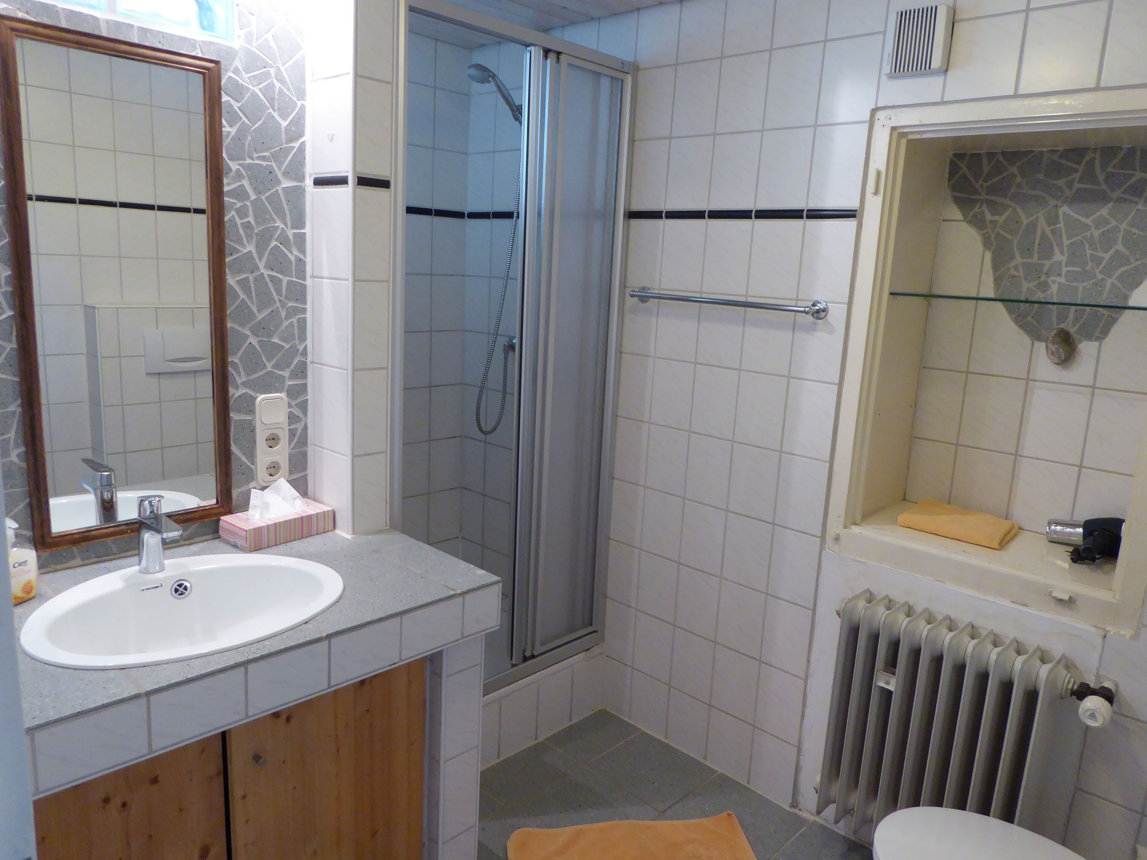 Un bagno con lavandino, specchio, doccia e toilette.