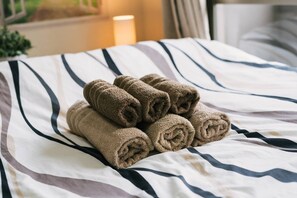 Una cama con toallas enrolladas y una colcha a rayas.