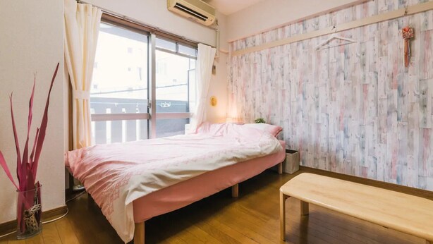 A bedroom with a bed, a bench, a potted plant, and a window with curtains. - Diamante Yakuin (Fukuoka)
