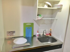 A compact kitchen with a sink, a weighing scale, and a green cutting board. - Diamante Yakuin (Fukuoka)