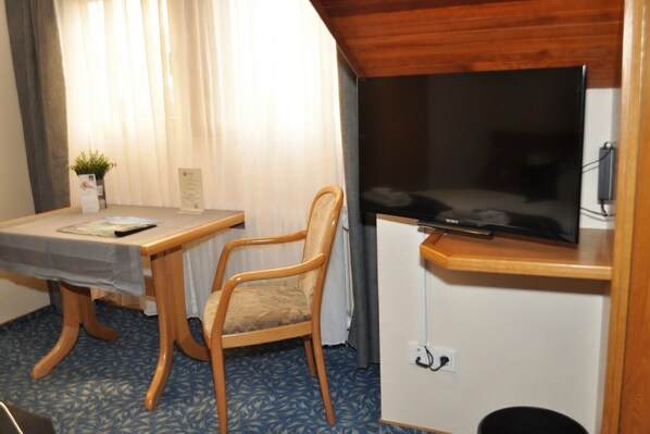 A room with a wooden table, a chair, a flat-screen TV mounted on a cabinet, and a small plant on the table. - Kühn's Mühle (Oestrich-Winkel)