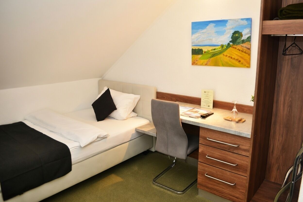 A small bedroom with a bed, a desk, and a chair.