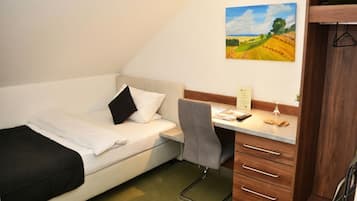 A small bedroom with a bed, a desk, and a chair.