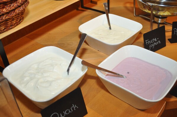 Tres tazones de yogur con diferentes sabores sobre una mesa de madera, con etiquetas.