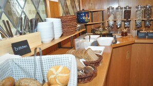 Un bufé de desayuno con pan, bollos y diferentes acompañamientos.