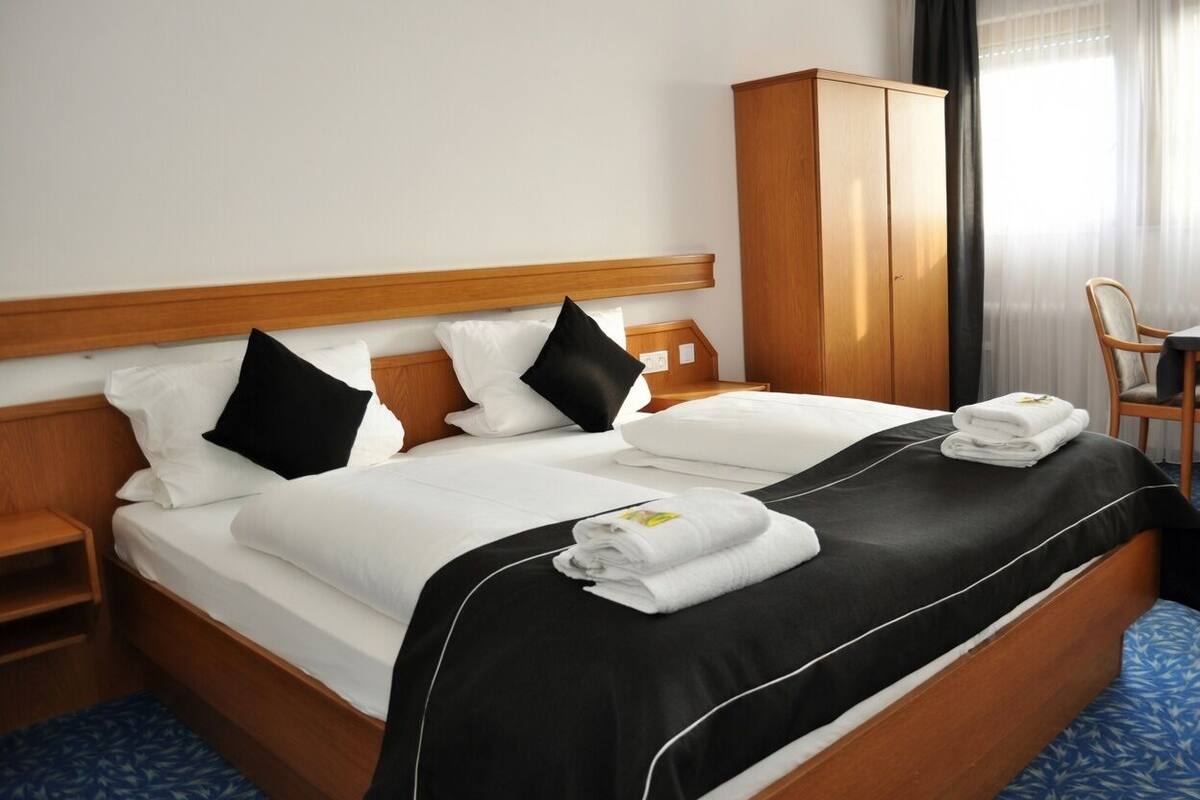 Une chambre d’hôtel avec un lit, une armoire, une chaise et un bureau.