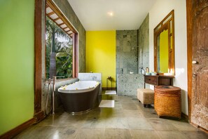 A bathroom with a large bathtub, a shower, and a vanity with a mirror.