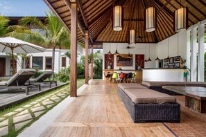 A covered outdoor area with lounge chairs, a dining table, and a kitchen area. - Luxury Villa in Bali near Beach, Bali Villa 2034 (Seminyak)