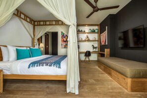 A bedroom with a canopy bed, a sofa bed, a ceiling fan, a TV, and a shelf with decorative items. - Luxury Villa in Bali near Beach, Bali Villa 2034 (Seminyak)