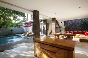 A modern indoor pool area with a wooden bar, seating, and a stone wall. - Luxury 2 Bedroom Villa With Private Pool, Bali Villa 2033 (Seminyak)