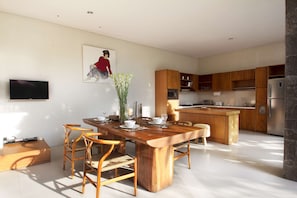 Una cocina moderna con armarios de madera, una isla central y un comedor con mesa y sillas de madera.