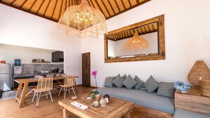 A cozy living room with a wooden coffee table, a sofa with cushions, and a dining area with chairs and a table. - Villa for Rent in Bali 2046 (Seminyak)