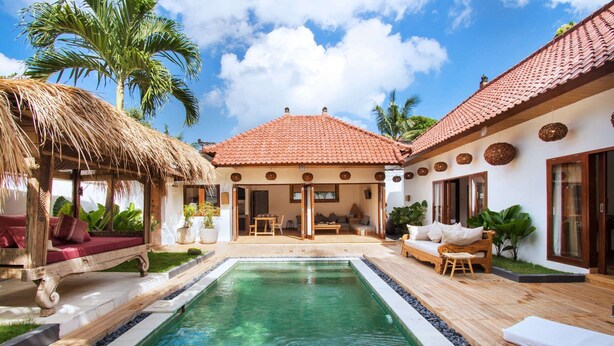 A pool area with a thatched structure, a wooden deck, and a covered seating area with cushions. - Villa for Rent in Bali 2046 (Seminyak)