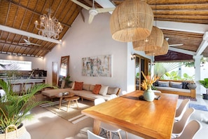 Amplia sala de estar con una mesa de comedor de madera, asientos cómodos y un ventanal con vistas a zonas verdes.