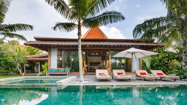 A resort with a pool, lounge chairs, and a covered seating area.