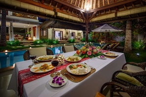 An outdoor dining area with a pool, dining tables, and chairs.