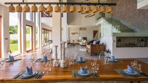 Un coin repas avec une table en bois dressée pour six personnes, entourée de grandes fenêtres.